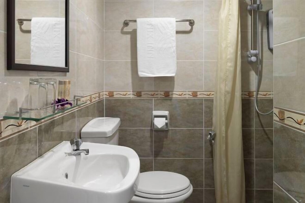 A bathroom with a sink, toilet, and shower. There are two towels hanging on towel bars.