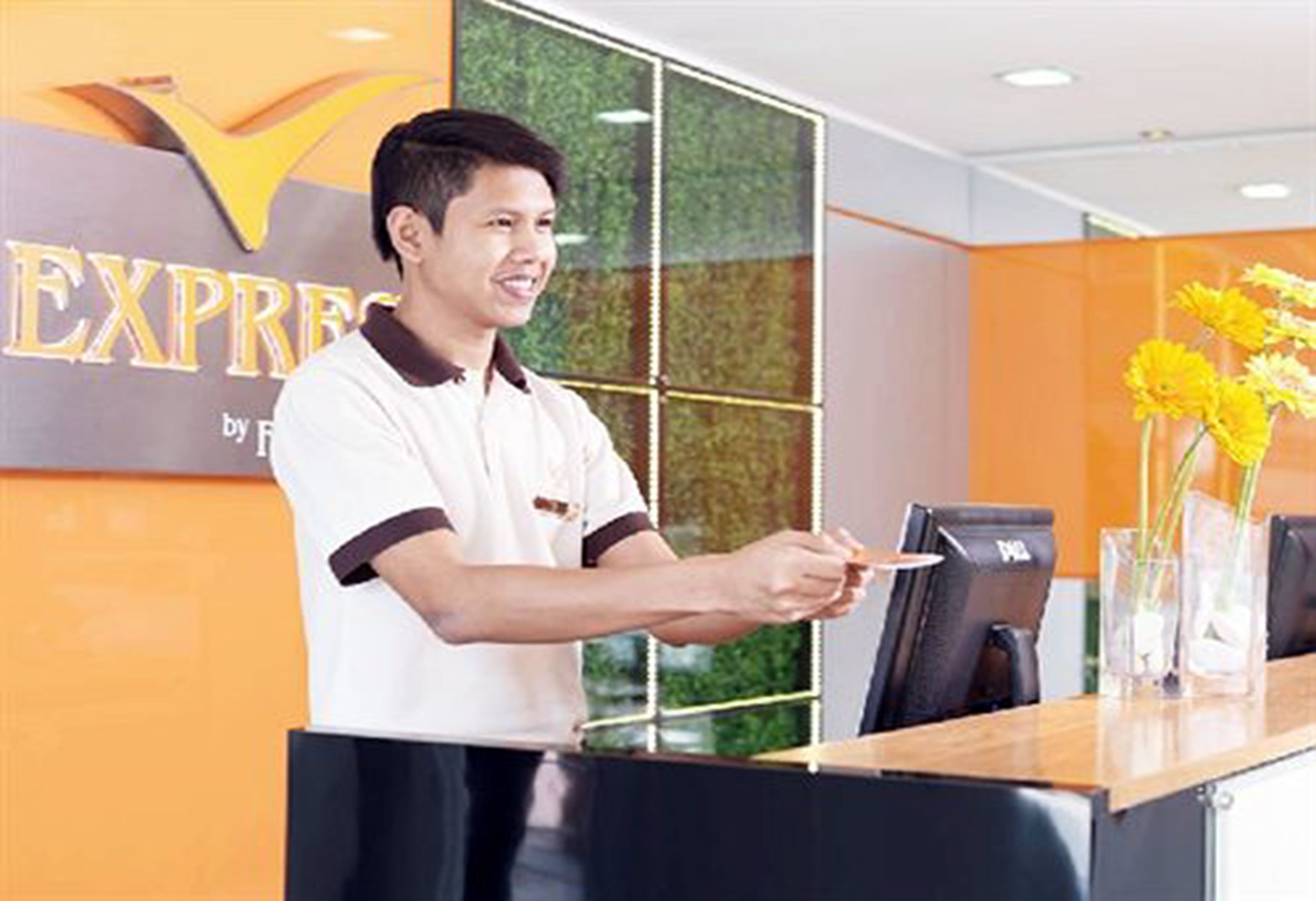 A hotel reception area with a reception desk, a glass partition, and a sign that reads "EXPRESS by Fret".