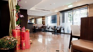 A modern hotel lobby with a marble floor, seating area, and large windows offering views of the outside. - KDM Hotel (Taipei)