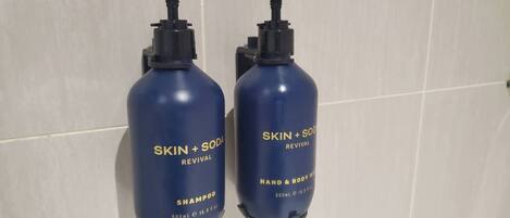 Två flaskor av schampot SKIN + SODA REVIVAL står på en vägg täckt med kakel.