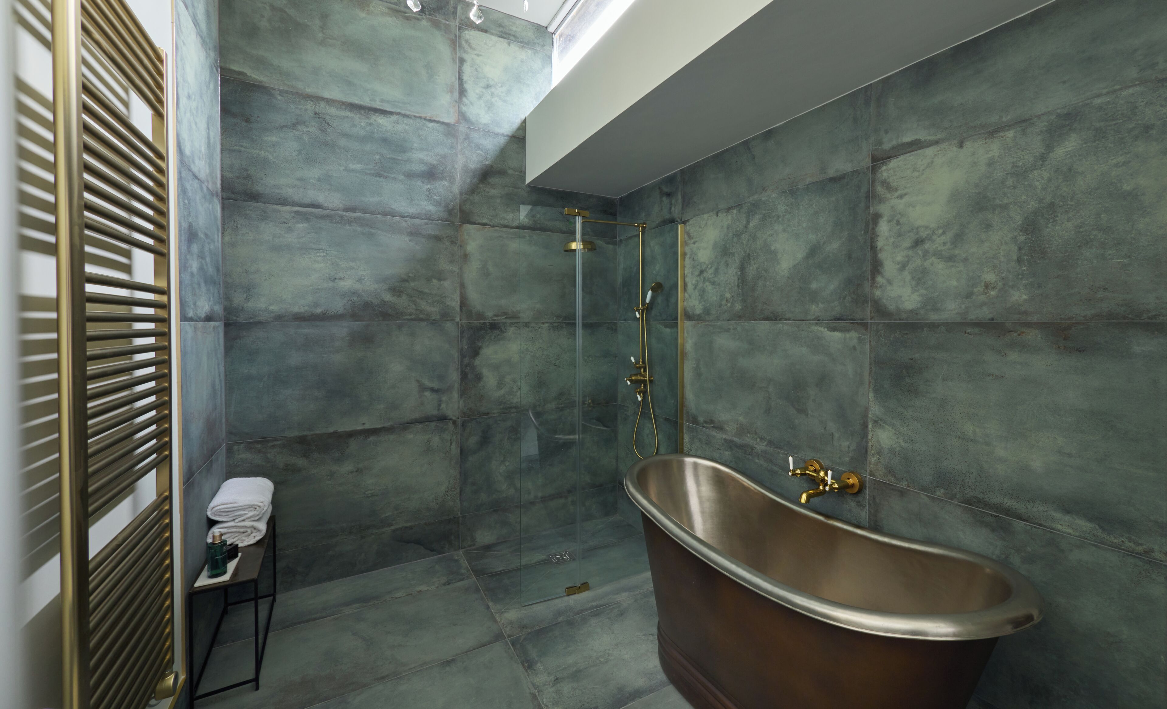 A modern bathroom with a freestanding bathtub, a glass-enclosed shower, and a towel rack with folded towels.