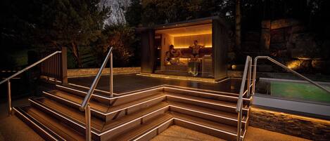 A modern outdoor pool area with steps leading to a covered seating area.