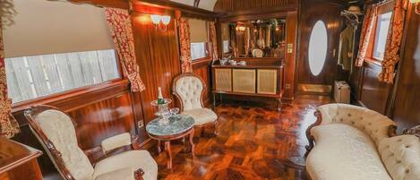 Elegante interior de tren con paneles de madera decorativos, asientos cómodos y una zona de bar.