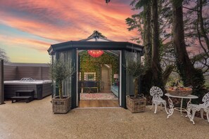 A gazebo with a view into a room, outdoor seating, and a hot tub.
