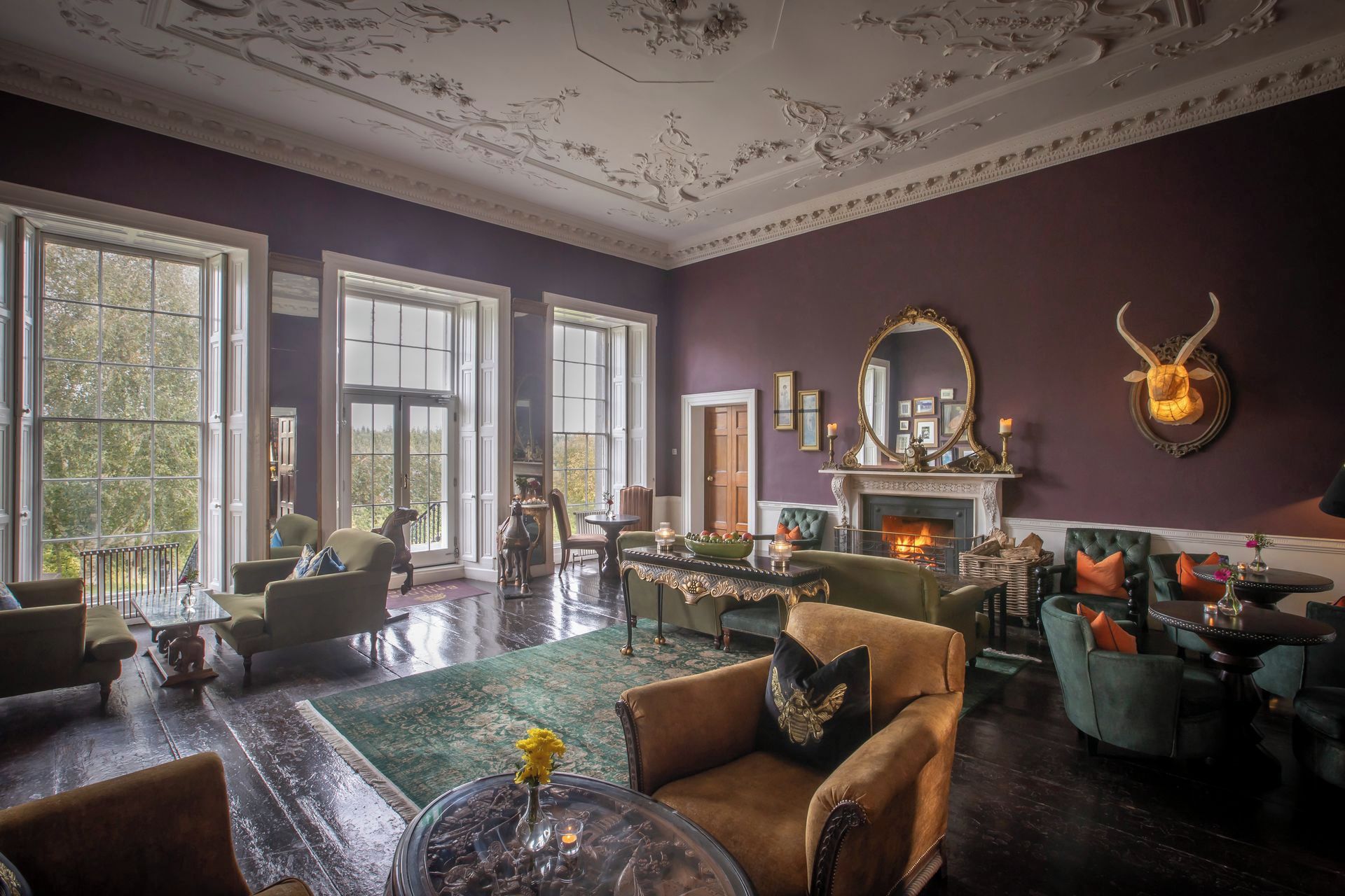 Un salón espacioso con chimenea, ventanas amplias y muebles clásicos.