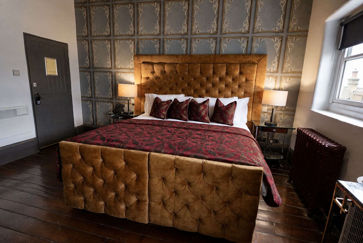Une chambre à coucher avec un grand lit, une tête de lit, des tables de chevet, un radiateur et une porte.