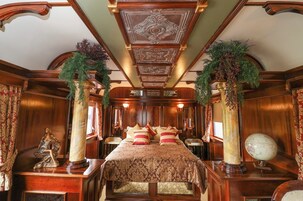Un dormitorio lujoso con una cama grande, techo decorado y columnas ornamentales.