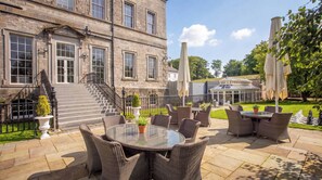 A stone building with a staircase leading to the entrance, outdoor wicker furniture, and a conservatory. - Bellinter House (Navan)