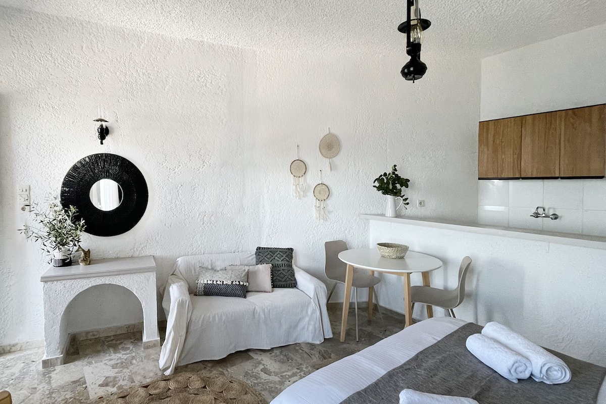 Ein modernes Schlafzimmer mit einem Bett, einem runden Teppich, einem kleinen Tisch und einer weißen Wand.