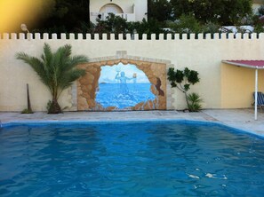 A swimming pool with a mural of a sea scene and a lighthouse. - Achlia Hotel (Ierapetra)
