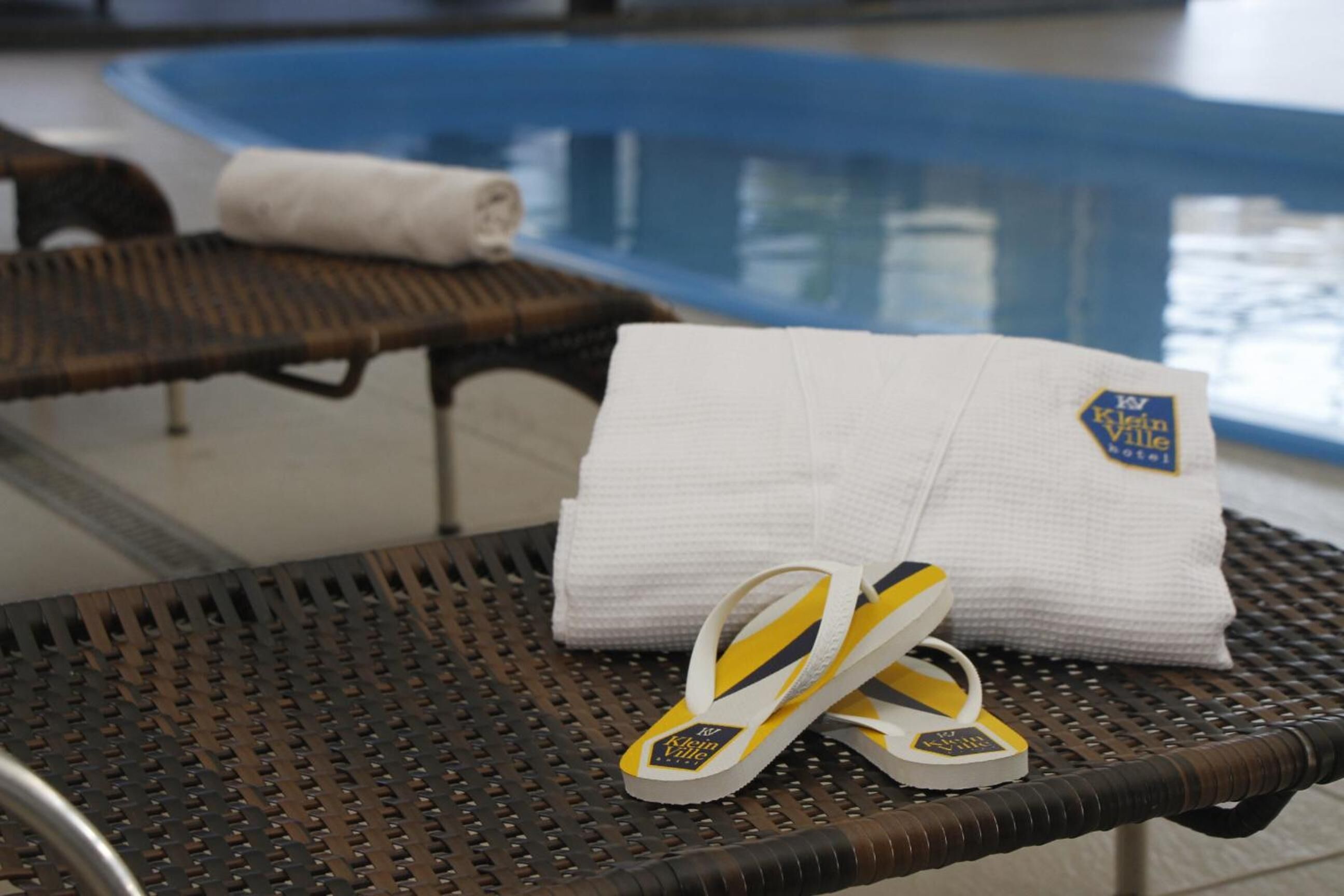 Un área junto a la piscina con una tumbona, una toalla y chanclas.