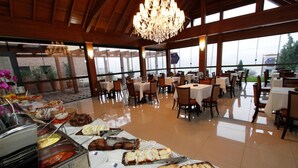 A buffet setup with various food items and a chandelier. - Sky Ville Gramado Hotel (Gramado)
