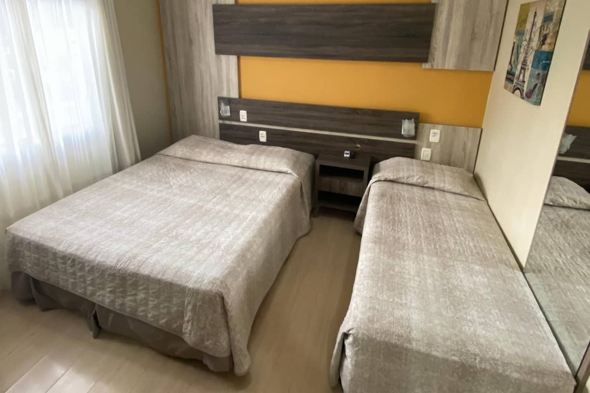 Ein Hotelzimmer mit zwei Einzelbetten, einem Holz-Kopfteil, einem Spiegel und einem Bild an der Wand.