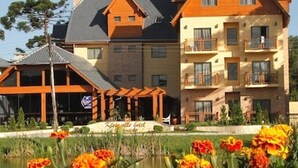 A hotel with a large building, a covered outdoor area, and a pond with marigolds. - Sky Ville Gramado Hotel (Gramado)