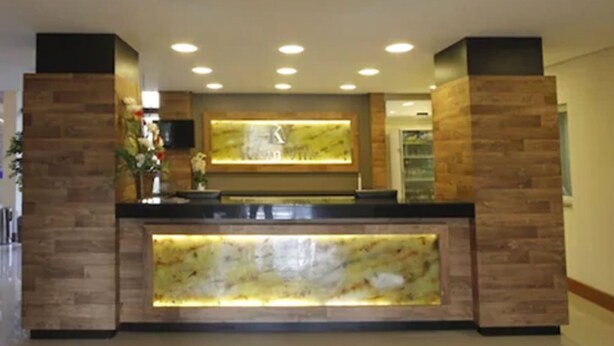 A reception area with a marble counter, wooden paneling, and a central chandelier. - Sky Ville Gramado Hotel (Gramado)