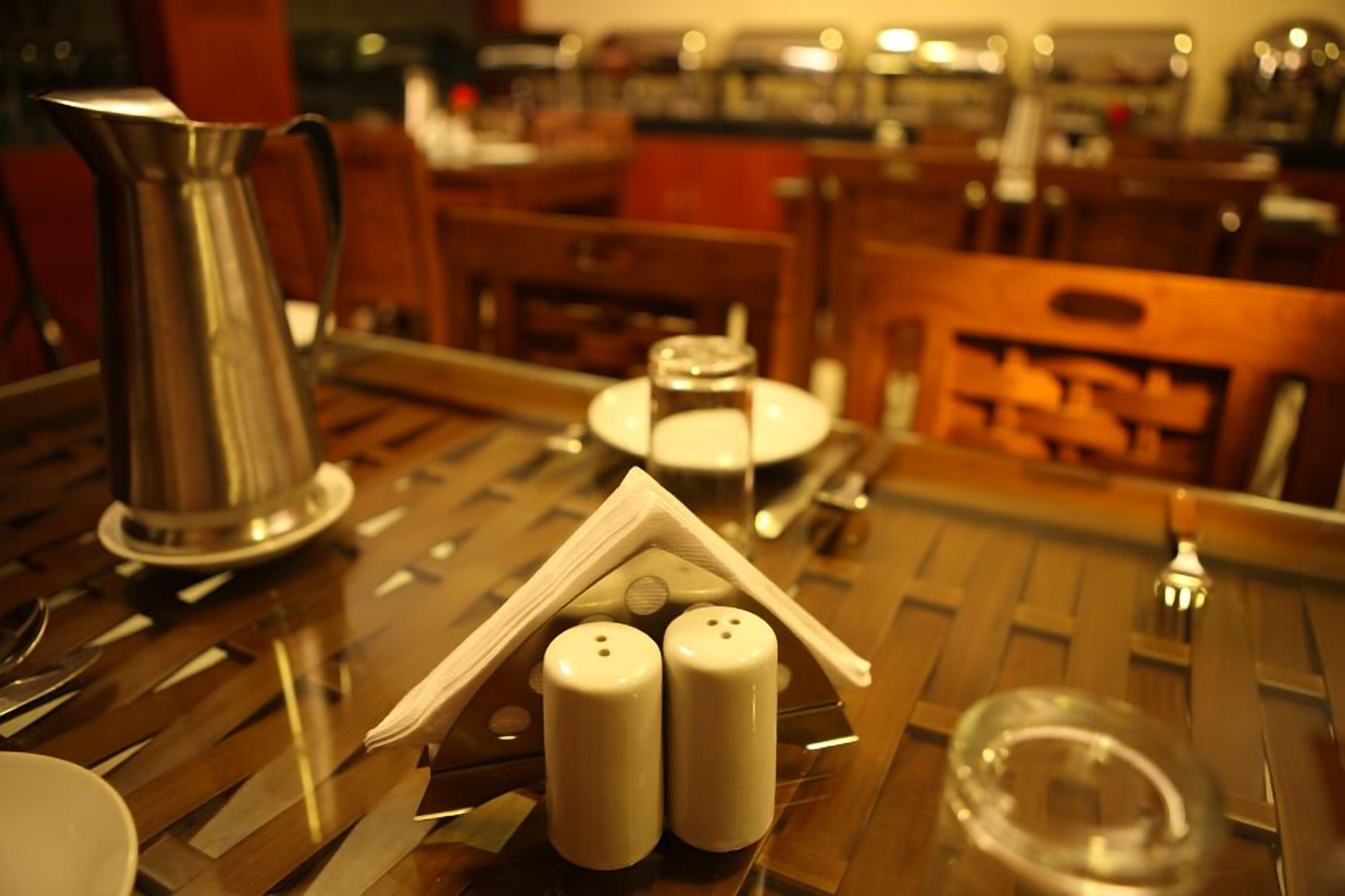 A table with a silver pitcher, salt and pepper shakers, and a clear glass.