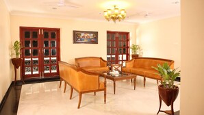 A living room with a sofa set, a coffee table, and two potted plants.
