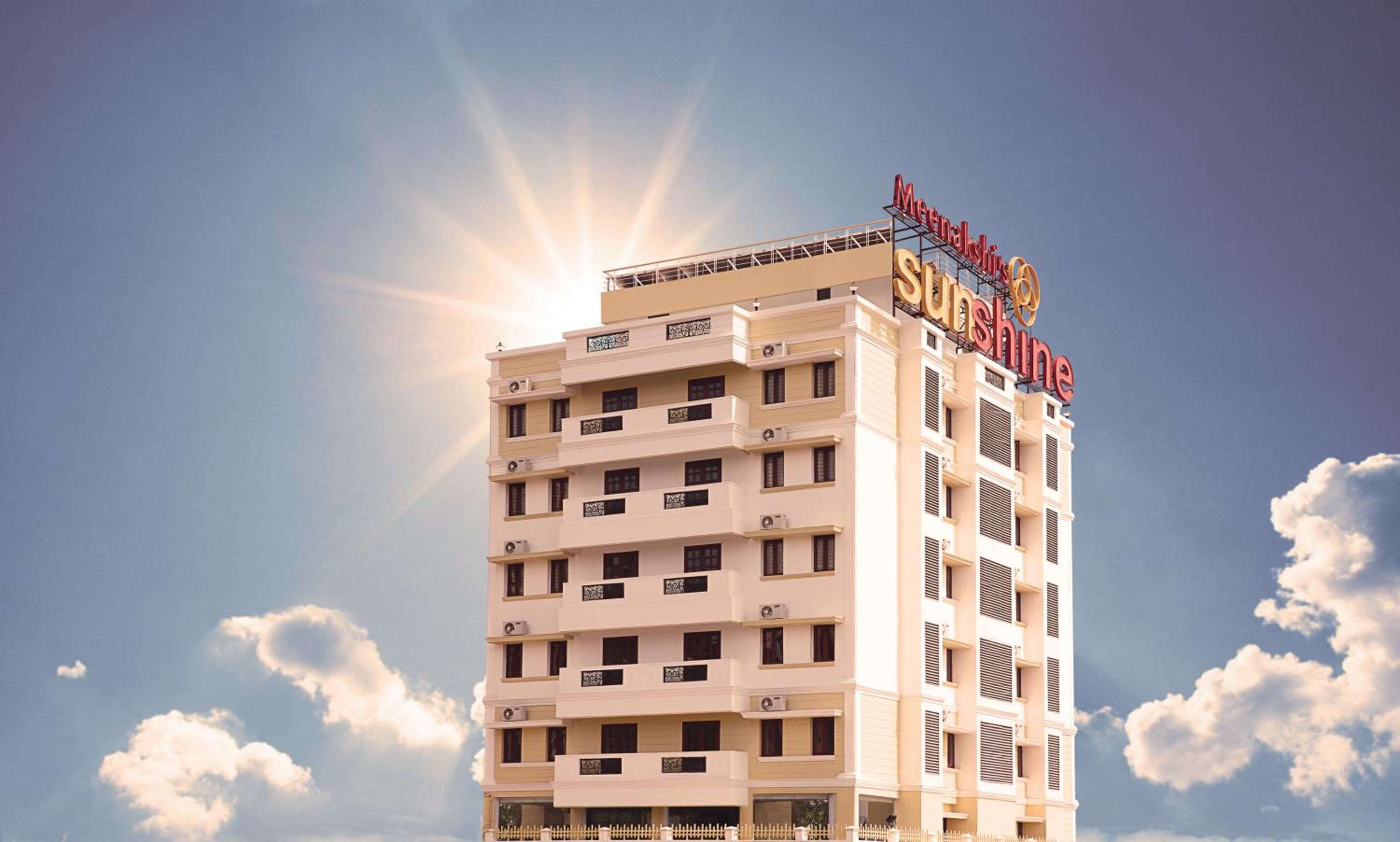A multi-story hotel with a prominent sign reading 'Meenakshi Sunshine.'
