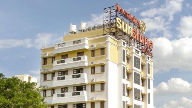 A multi-story hotel with a sign reading "Meenakshi Sunshine Hotel".