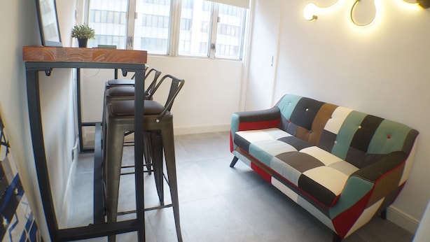 A small, modern living area with a sofa, a dining table with chairs, and a potted plant. - Tung Wo Guest House (Kowloon)