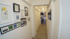A hallway with framed artwork on the walls, leading to a kitchen area. - Tung Wo Guest House (Kowloon)