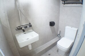 Un bagno piccolo e pulito con lavandino, water e asciugatore di mani, tutto in bianco.