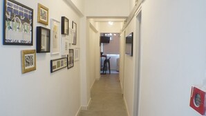 A hallway with framed artwork on the walls, leading to a kitchen area. - Tung Wo Guest House (Kowloon)