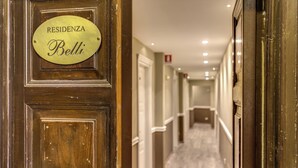 Um corredor com uma placa de latão na porta de madeira, com a inscrição 'RESIDENZA Bellì'.