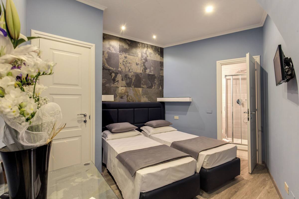 Een slaapkamer met twee bedden, een grote spiegel en een douche.