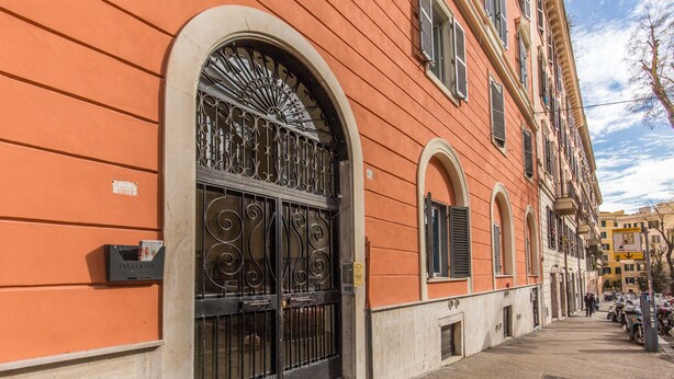 Uma rua estreita com uma fileira de edifícios com janelas em arco e um portão preto imponente.