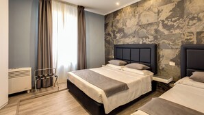 Quarto de hotel moderno com uma cama grande, mesa de cabeceira, banco embutido e parede com textura de pedra.
