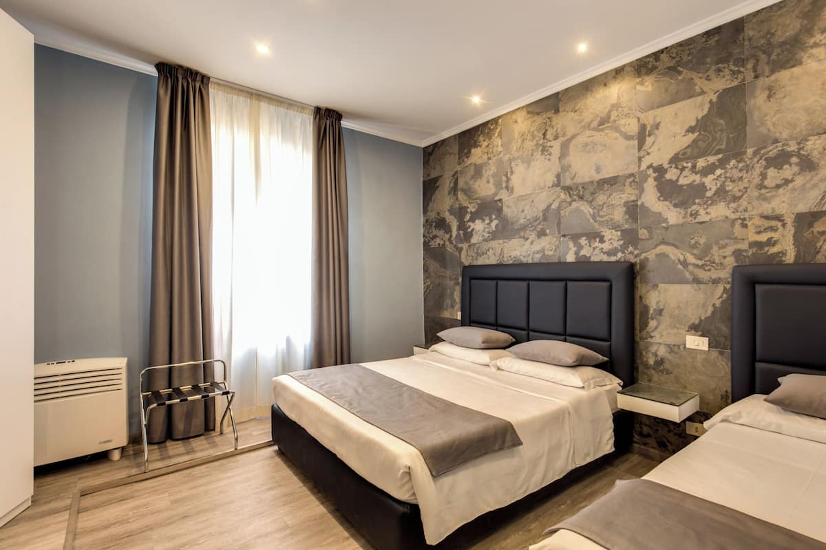 Een moderne hotelkamer met een groot bed, een nachtkastje, een ingebouwde bank en een wand met een stenen patroon.