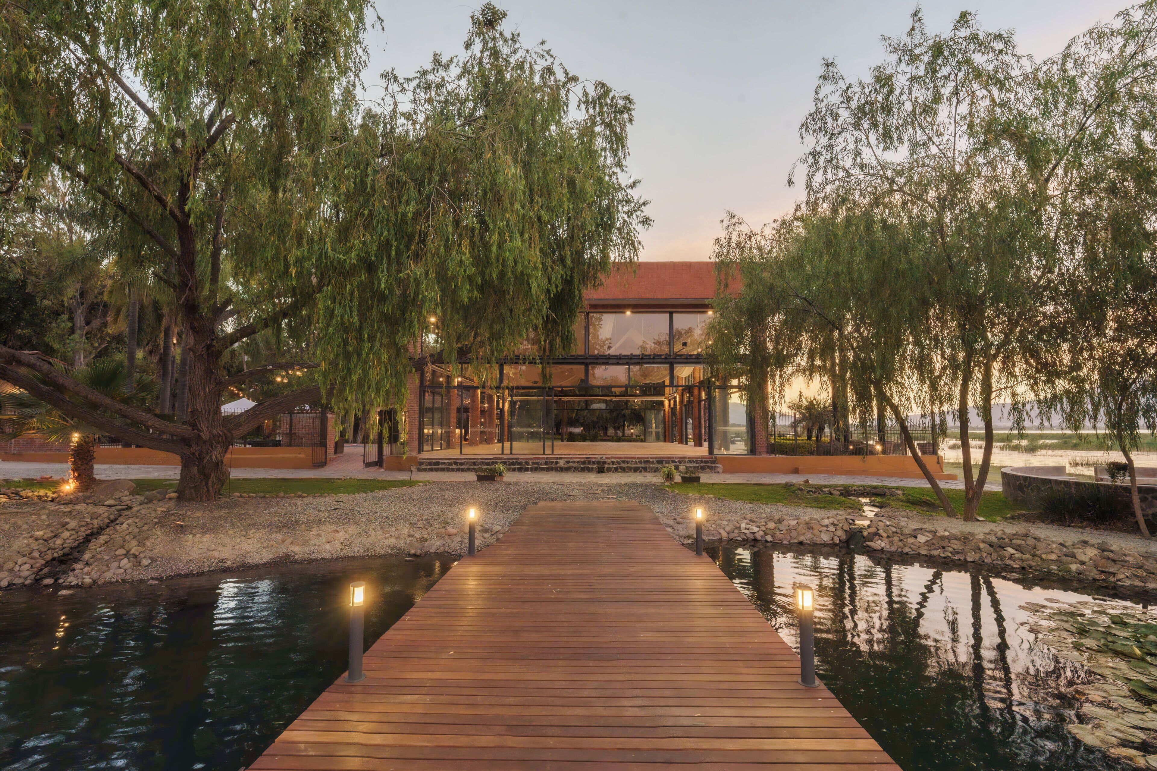 A modern building with a glass facade, a wooden deck, and a pond.