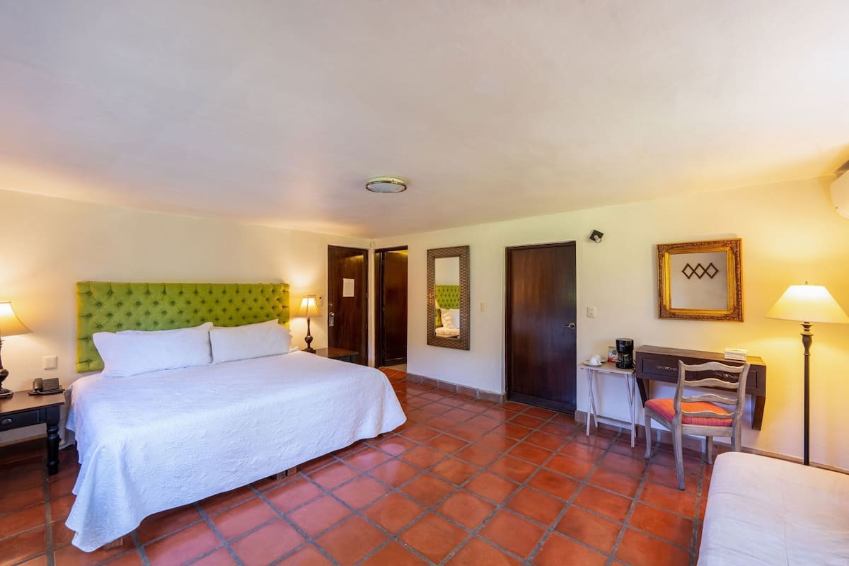 A hotel room with a bed, desk, chair, and two doors.