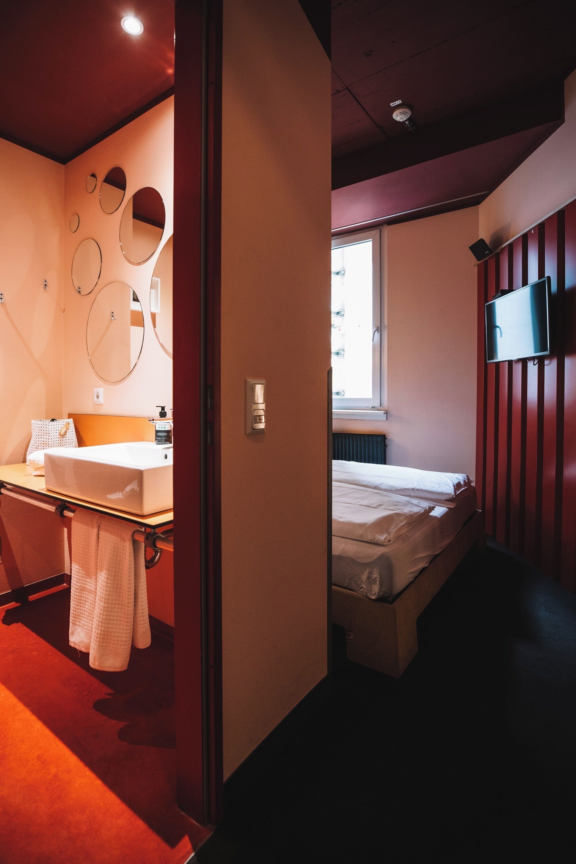 A hotel room with a bed, a bedside table, a mirror, and a television.