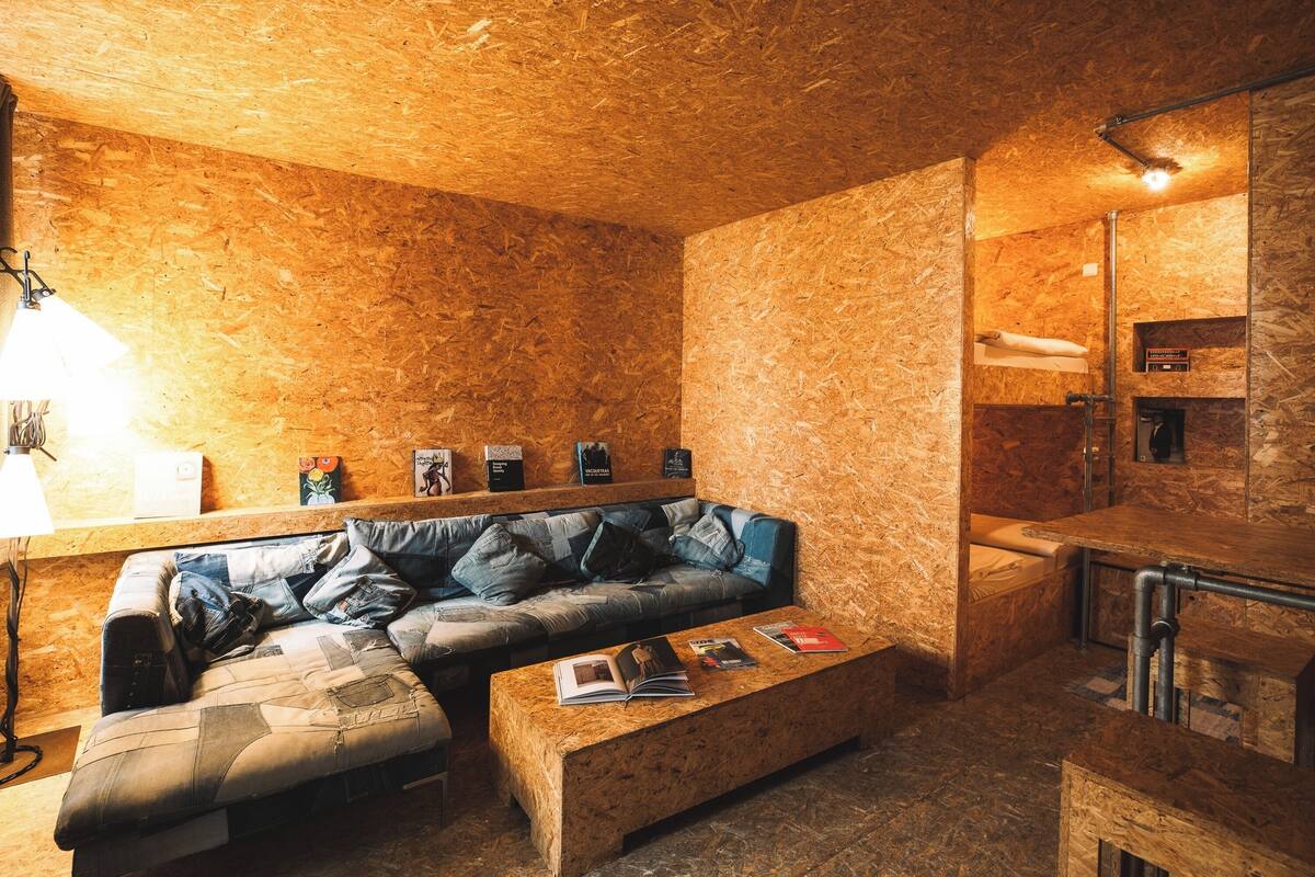 A cozy room with a wooden wall, a sofa, a coffee table, and a mirror.