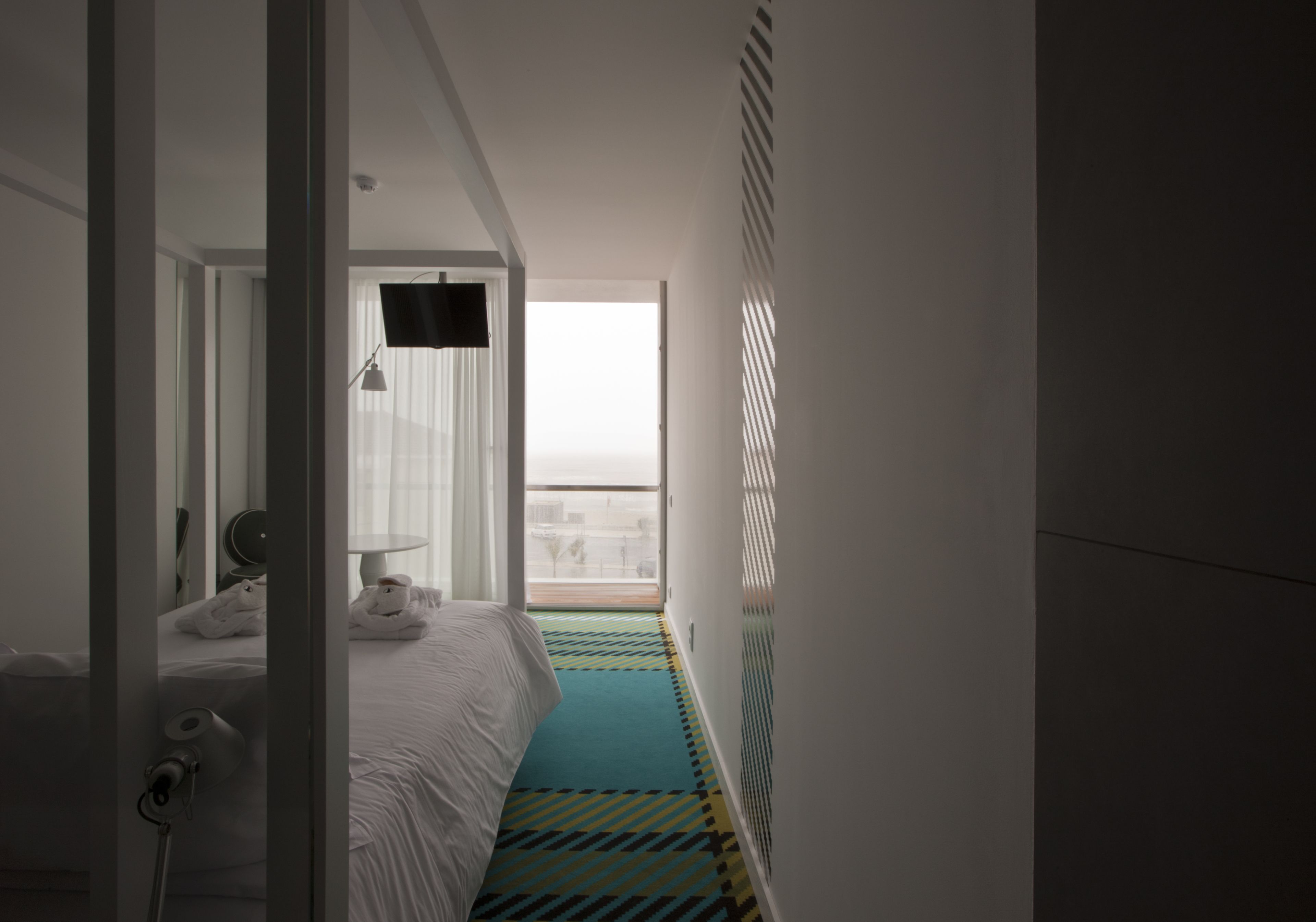 Habitación de hotel con cama, televisión, ventana y vista a la ciudad.