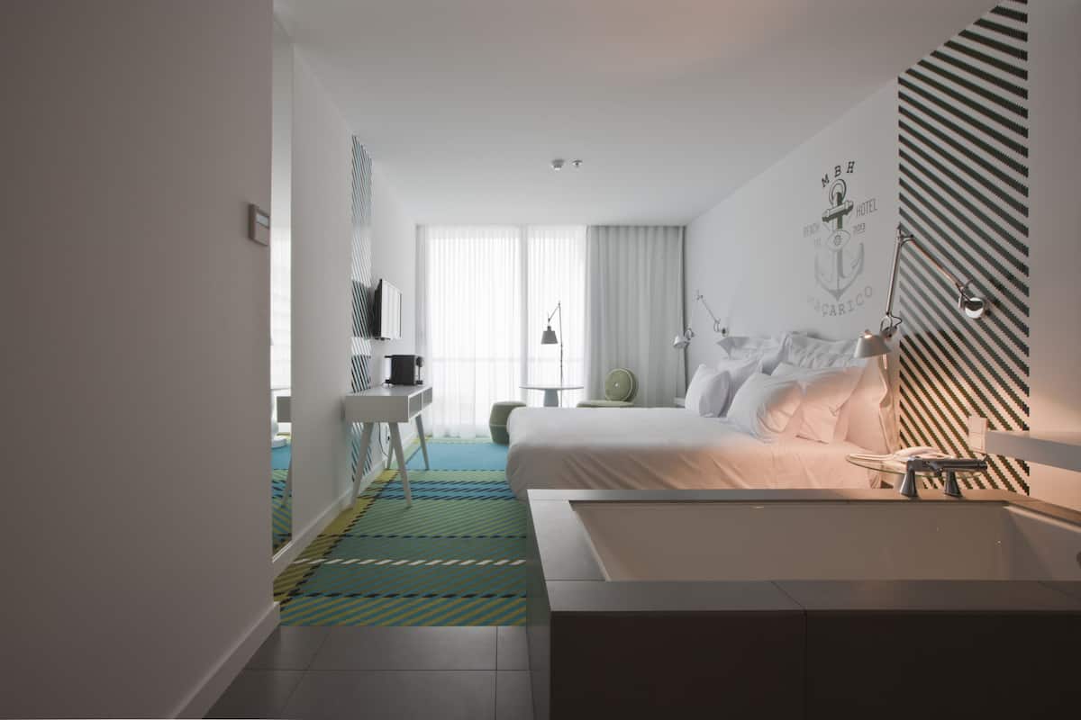 Moderni hotellihuone, jossa on suuri sänky, työpöytä ja kylpyhuone.