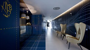 Un pasillo moderno de hotel con una recepción, zona de estar y diseños decorativos en las paredes.