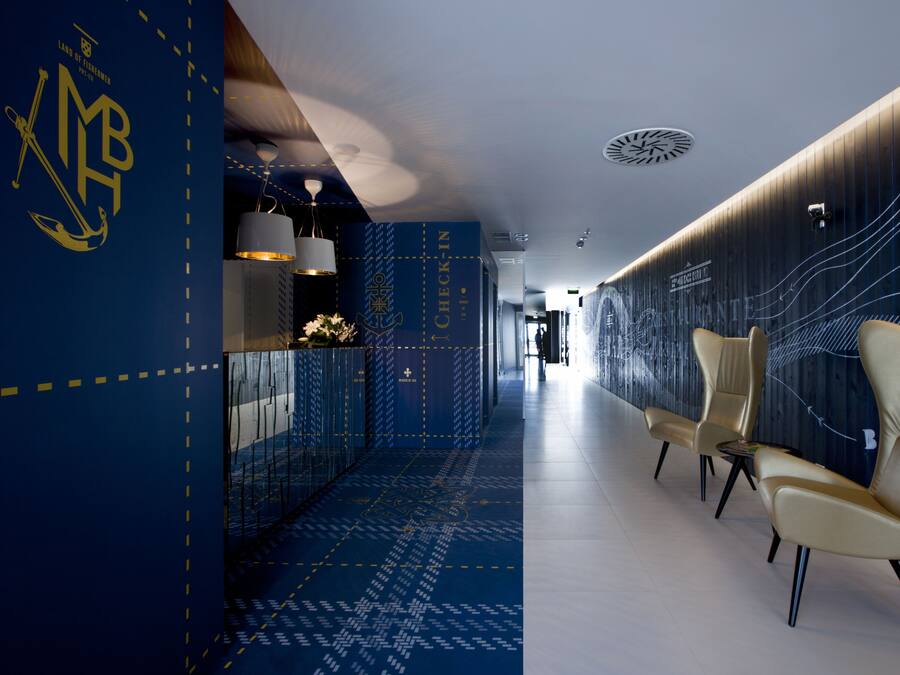 Un pasillo moderno de hotel con una recepción, zona de estar y diseños decorativos en las paredes.