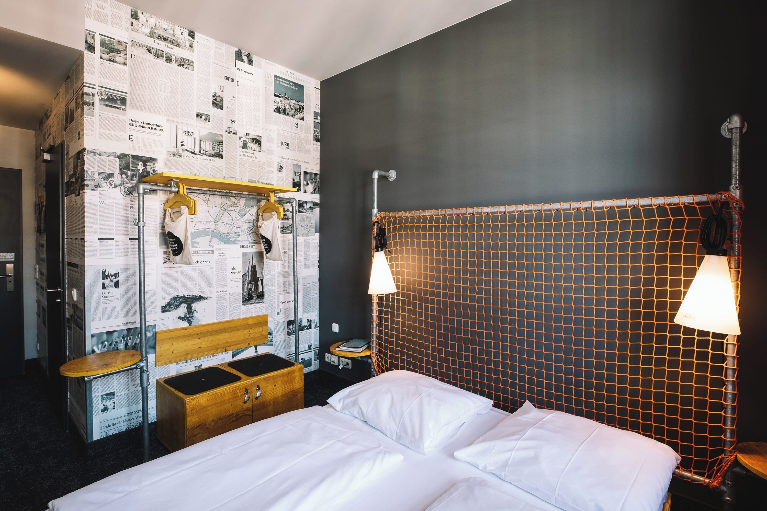 Ein Hotelzimmer mit Bett, Nachttisch aus Holz und einer Wand voller Zeitungsartikel.