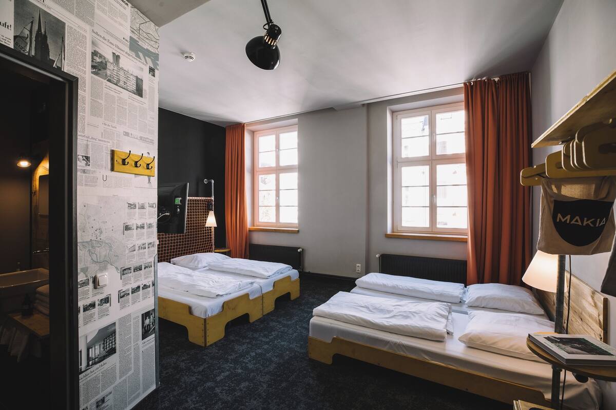 A hotel room with two beds, a map on the wall, and a window with curtains.