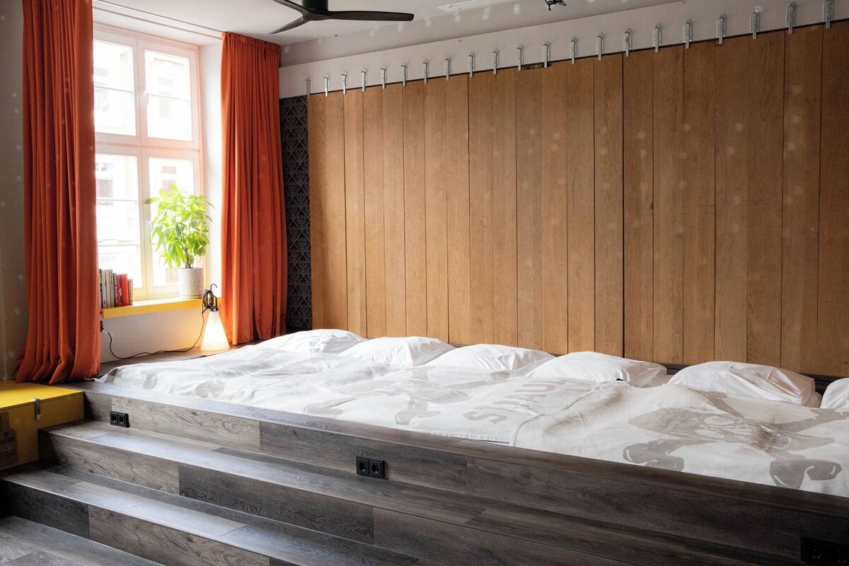 A bedroom with a wooden headboard, a bed with white bedding, and a window with curtains.