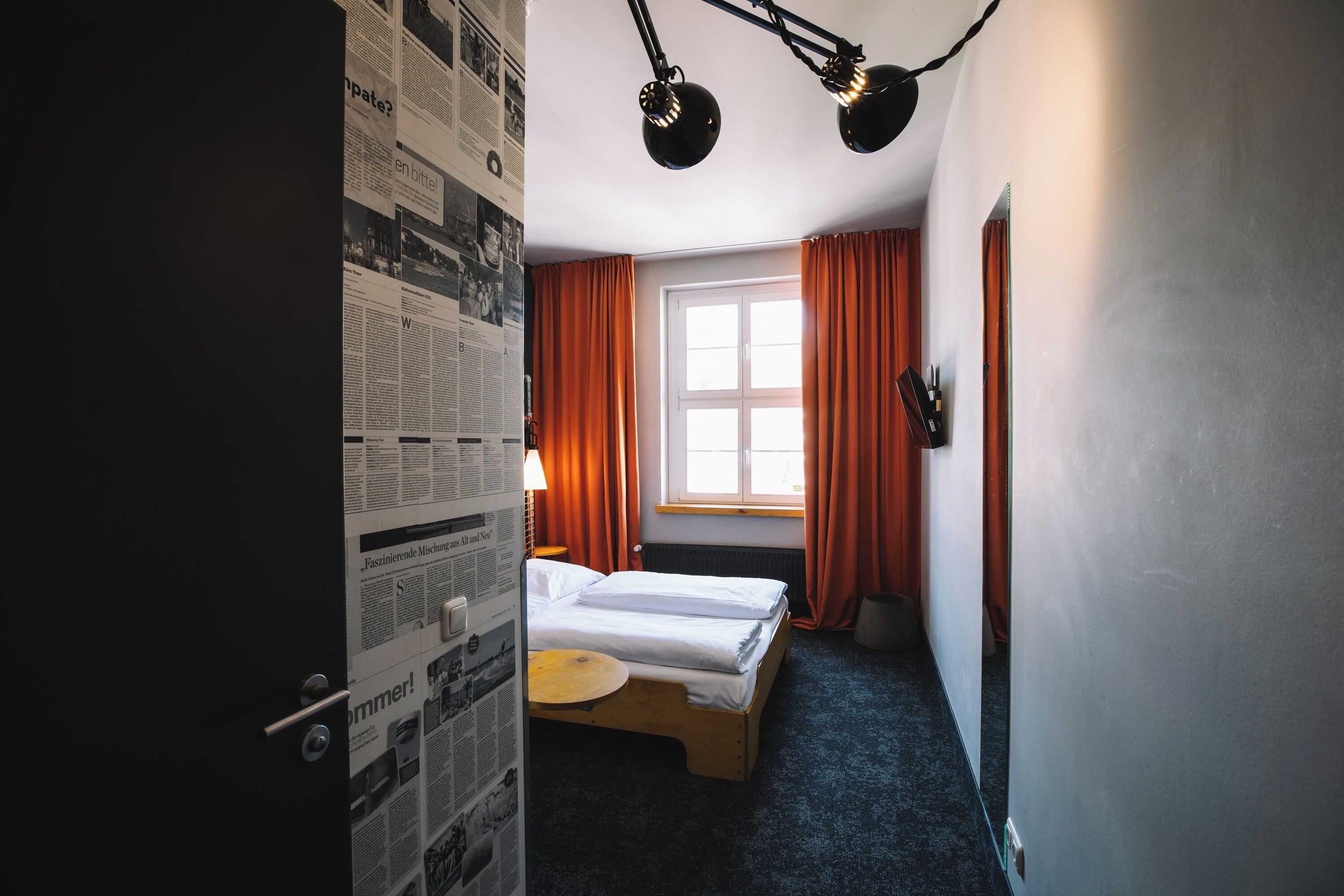 Una habitación de hotel con una cama, una mesita y una ventana con cortinas.