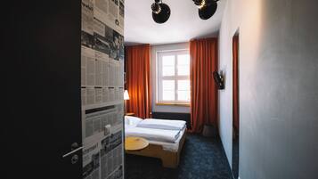 Una habitación de hotel con una cama, una mesita y una ventana con cortinas.