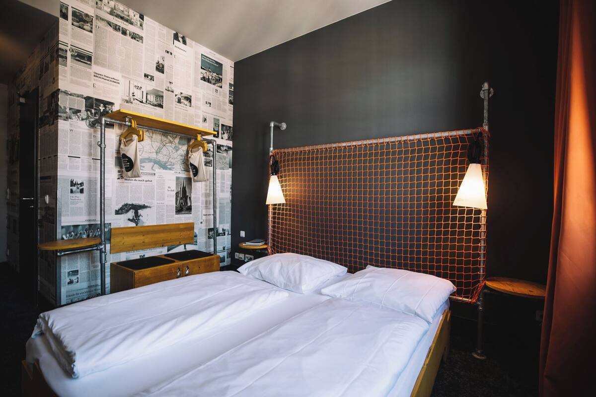 A hotel room with a bed, a wooden dresser, a map on the wall, and a netted headboard.