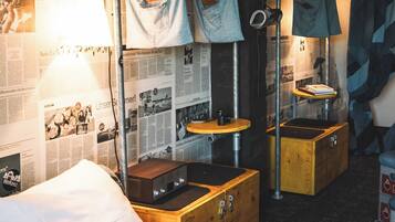 Ein Zimmer mit einem Bett, Holzschränken und einem Kleiderständer mit Kleidung.