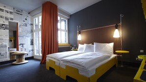 A room with a bed, a small table, a chair, a window with curtains, and a wall with a map. - Superbude St. Pauli (Hamburg)