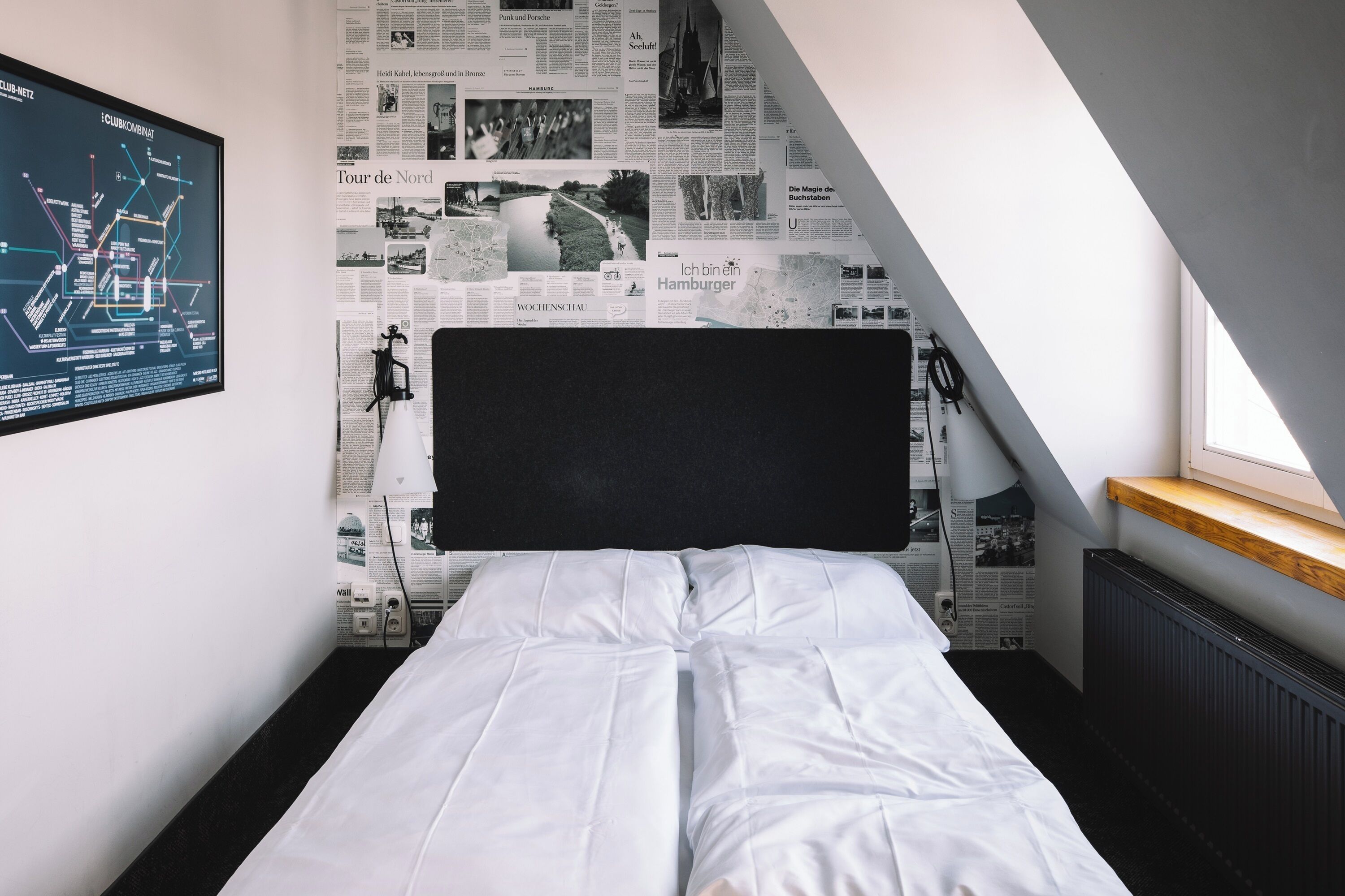 Una habitación con una cama, un mapa en la pared y recortes de periódico.