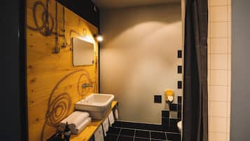 A modern bathroom with a wooden vanity, a mirror, a sink, and a shower area.